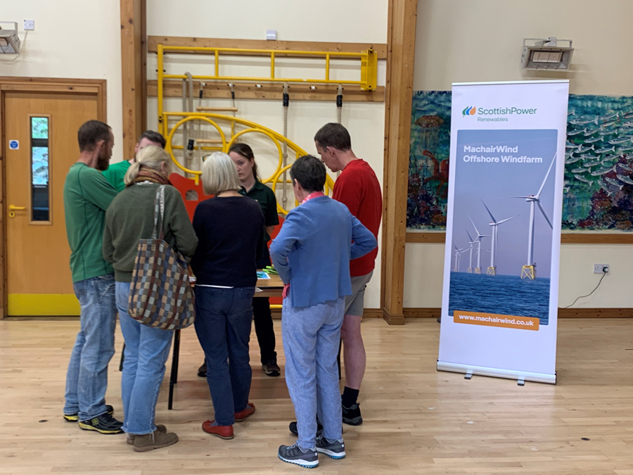 Members of the community gather around MachairWind team booth to learn about the project